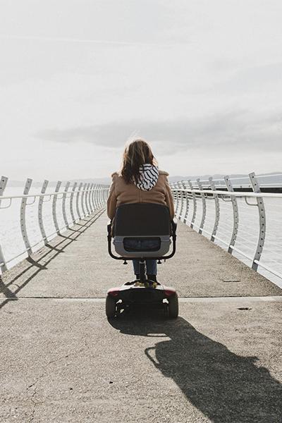 A person with a disability rides a mobility scooter down the breakwater in Victoria, BC