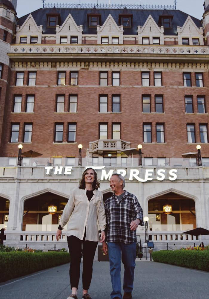 A couple walking down the pathway outside of the Fairmont Empress in Victoria, BC