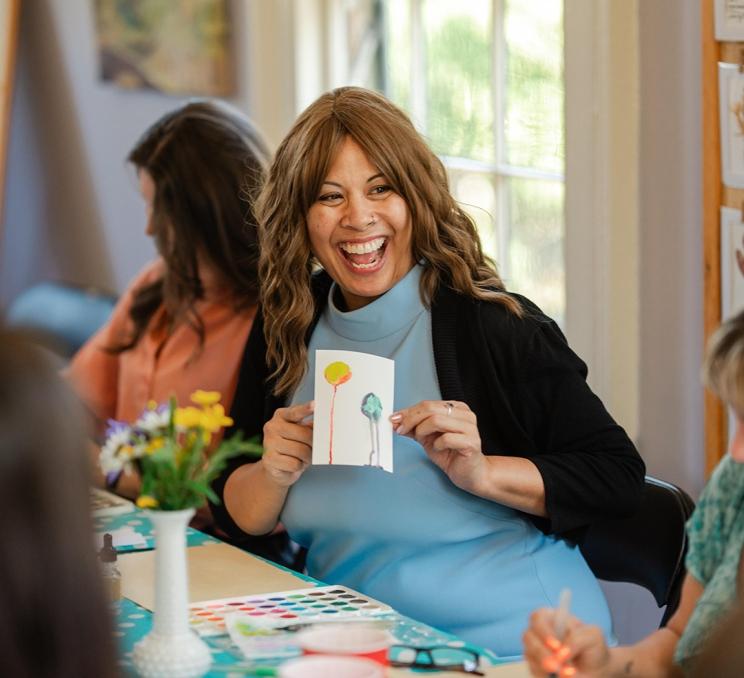 A woman shows off a water colour painting she made during at art class at Emily Carr House, a National Historic Site in Victoria, BC
