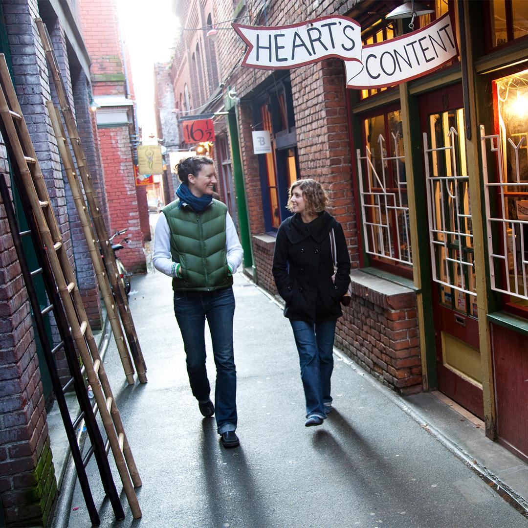 Two people walk through Fan Tan Alley, the narrowest street in Canada, in Victoria BC's historic Chinatown