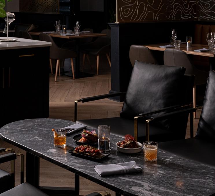 Appetizers and glasses of whiskey line a table at Fathom in Victoria, BC