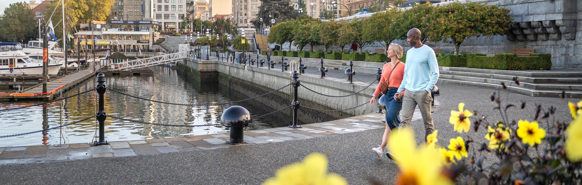 A couple walks along the Inner Harbour Lower Causeway in Victoria, BC
