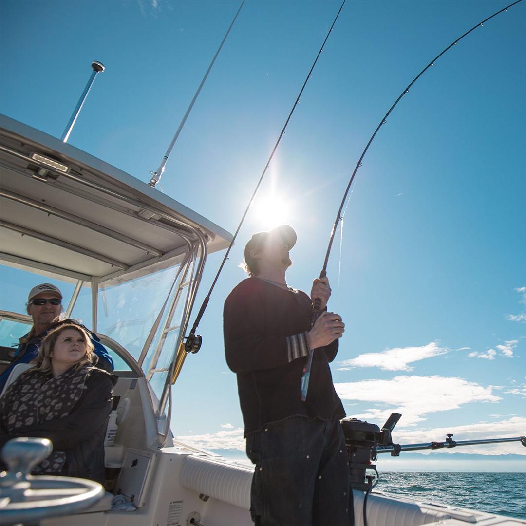 A man fishes off the back of a boat in the Salish Sea off the coast of Victoria, BC