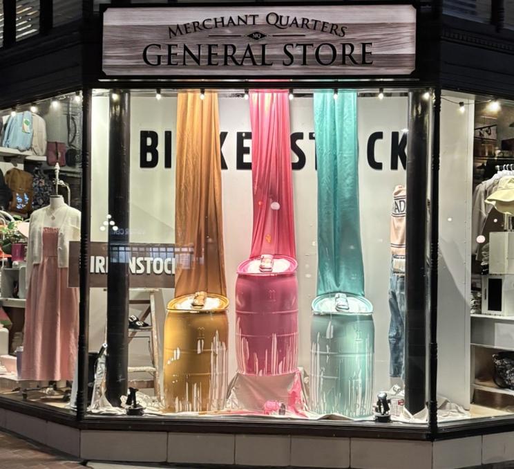 The front window of Merchant Quarters General Store in Victoria, BC with a Birkenstocks display coloured un yellow, pink, and blue.