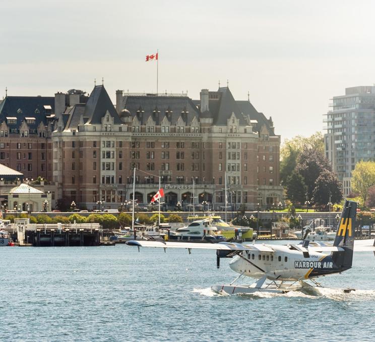 A Harbour Air Seaplanes flight lands on the water on the Inner Harbour with the Fairmont Empress Hotel in the background in Victoria, BC