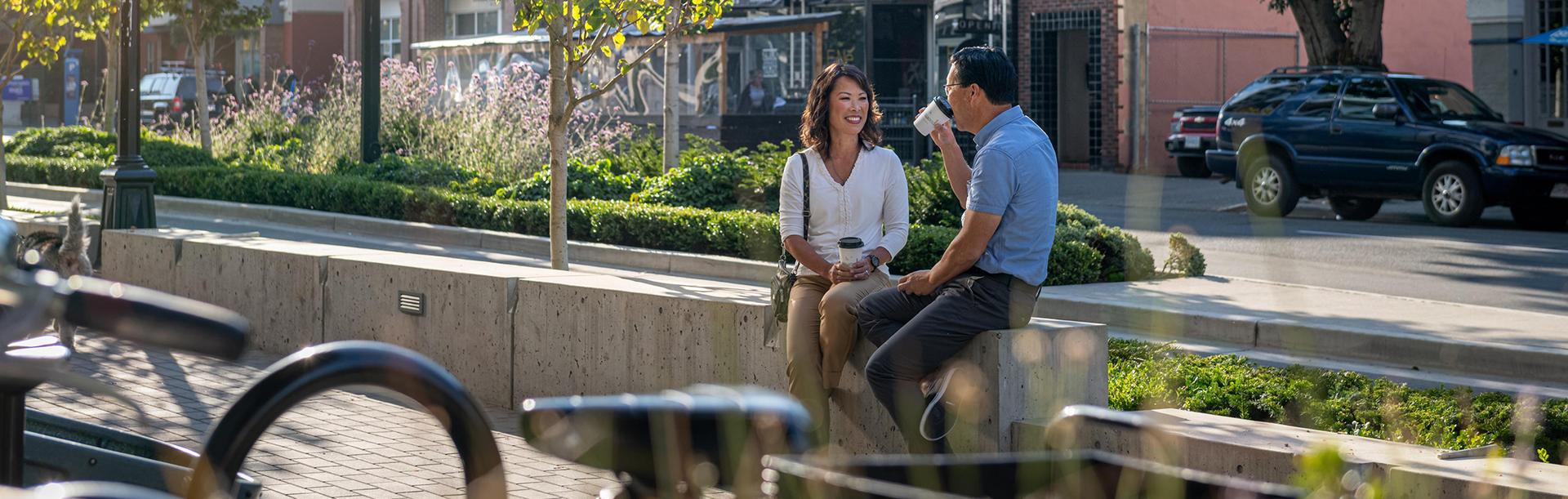 A couple enjoys a coffee along the street in Victoria, BC