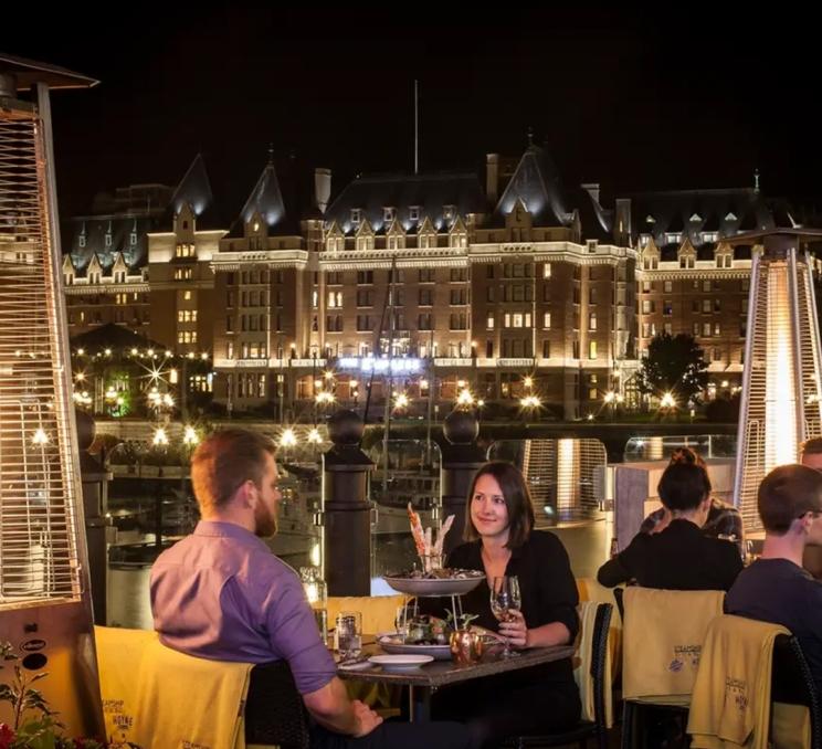 A couple sits on the patio at Seamship Grill & Bar in Victoria, BC after dark
