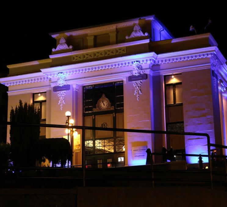 The historic Steamship Terminal Building illuminated by blue light at night on the Inner Harbour in Victoria, BC