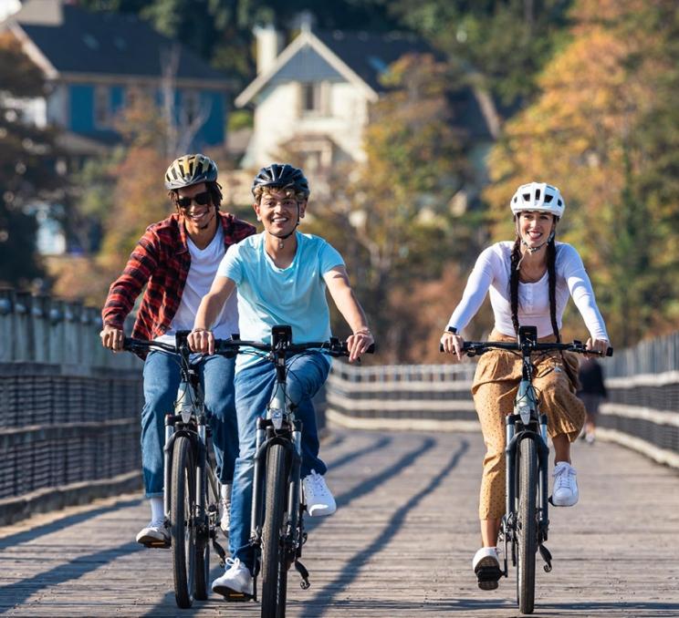 Three friends ride bikes along the Selkirk Trestle in Victoria, BC