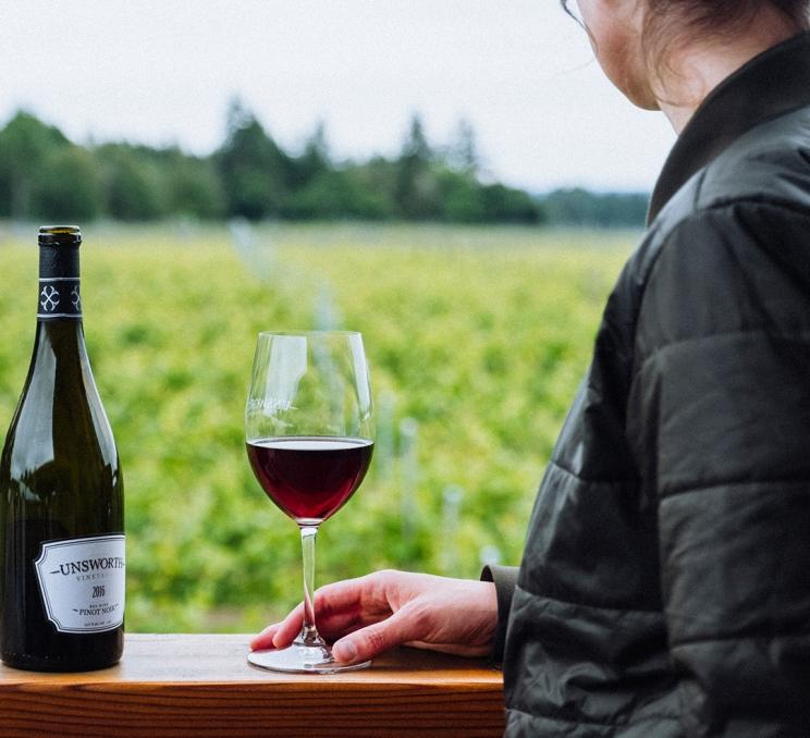 A woman enjoys a glass of wine at Unsworth Vineyards in Victoria, BC