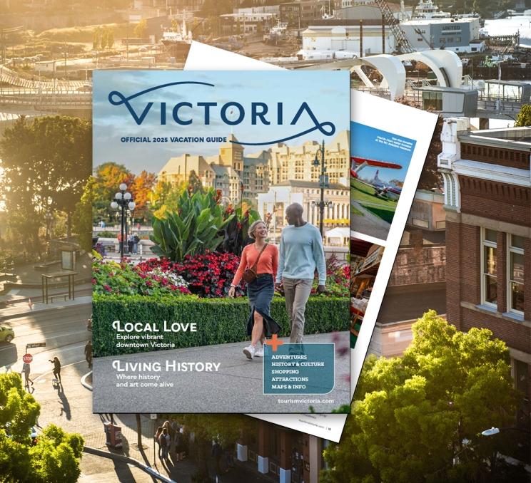 Two pages of the 2025 Victoria Vacation Guide at overlayed on top of an aerial image of Yates Street in downtown Victoria, BC