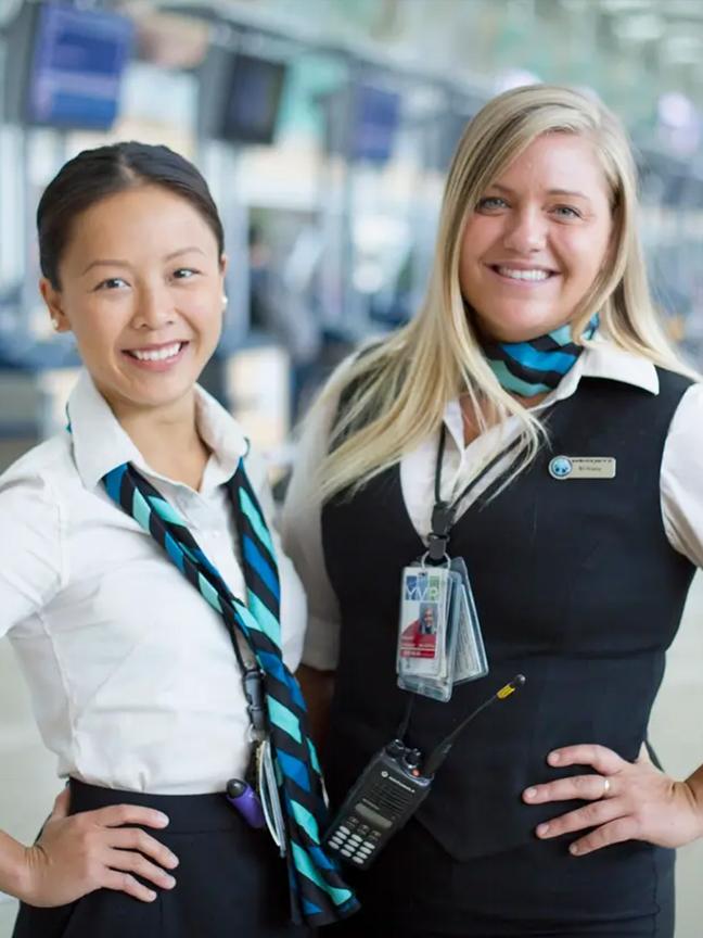 Two flight attendants stand together in an airport